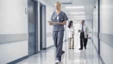 Healthcare provider walking through a hallway with two other healthcare providers standing behind them