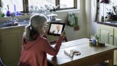 A woman talking to a provider through a video call on a tablet.