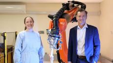 University of Sydney professors Elizabeth Clarke and Bill Walter pose beside the robotic arm KOBRA