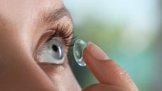 Person inserting a contact lens into their eye