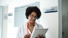 Healthcare provider on a tablet walking through a clinic
