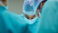 Surgeons in scrubs looking down at a patient in the operating room